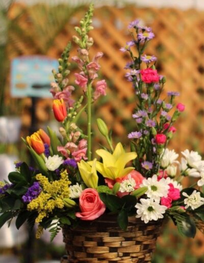 Floral basket with snapdragons, roses, and colorful flowers.