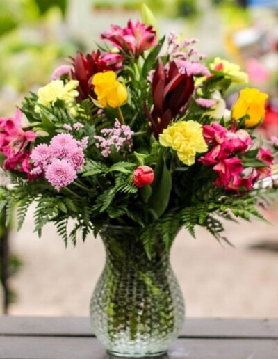 Floral vase with yellow, red, and pink flowers.