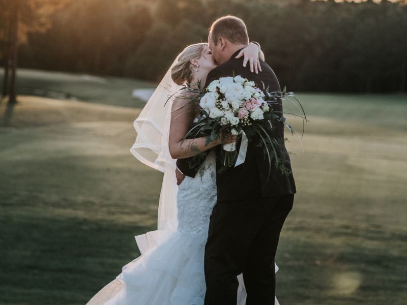 bride and groom kissing with floral bouquet