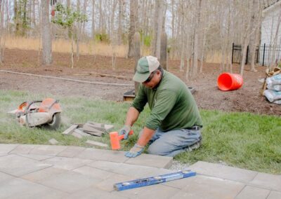 Cross Creek employee hammering a paver into a patio.