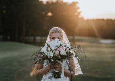 Bride with floral arrangement from Cross Creek Florist.